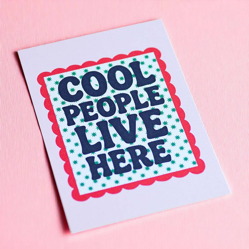 Colourful Cool People Live Here A5 art print with playful retro typography and bright scalloped detailing displayed on a pink background.
