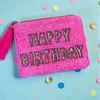 Bright pink beaded zip pouch with sparkling ‘Happy Birthday’ lettering and pink tassel zip pull on a colourful background.