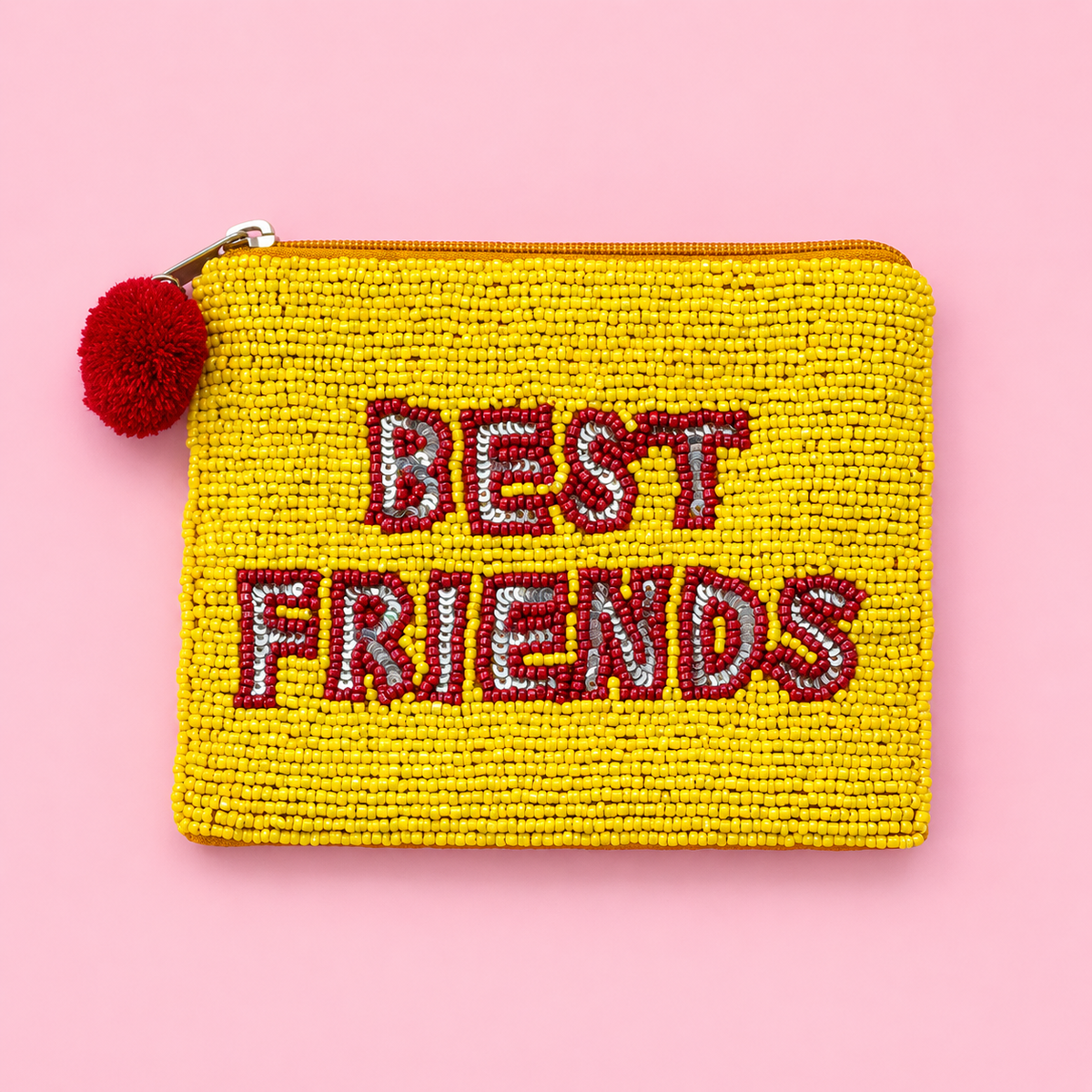 Yellow beaded zip pouch with red and silver Best Friends lettering and fluffy red pom pom zip pull on a pink backgroun