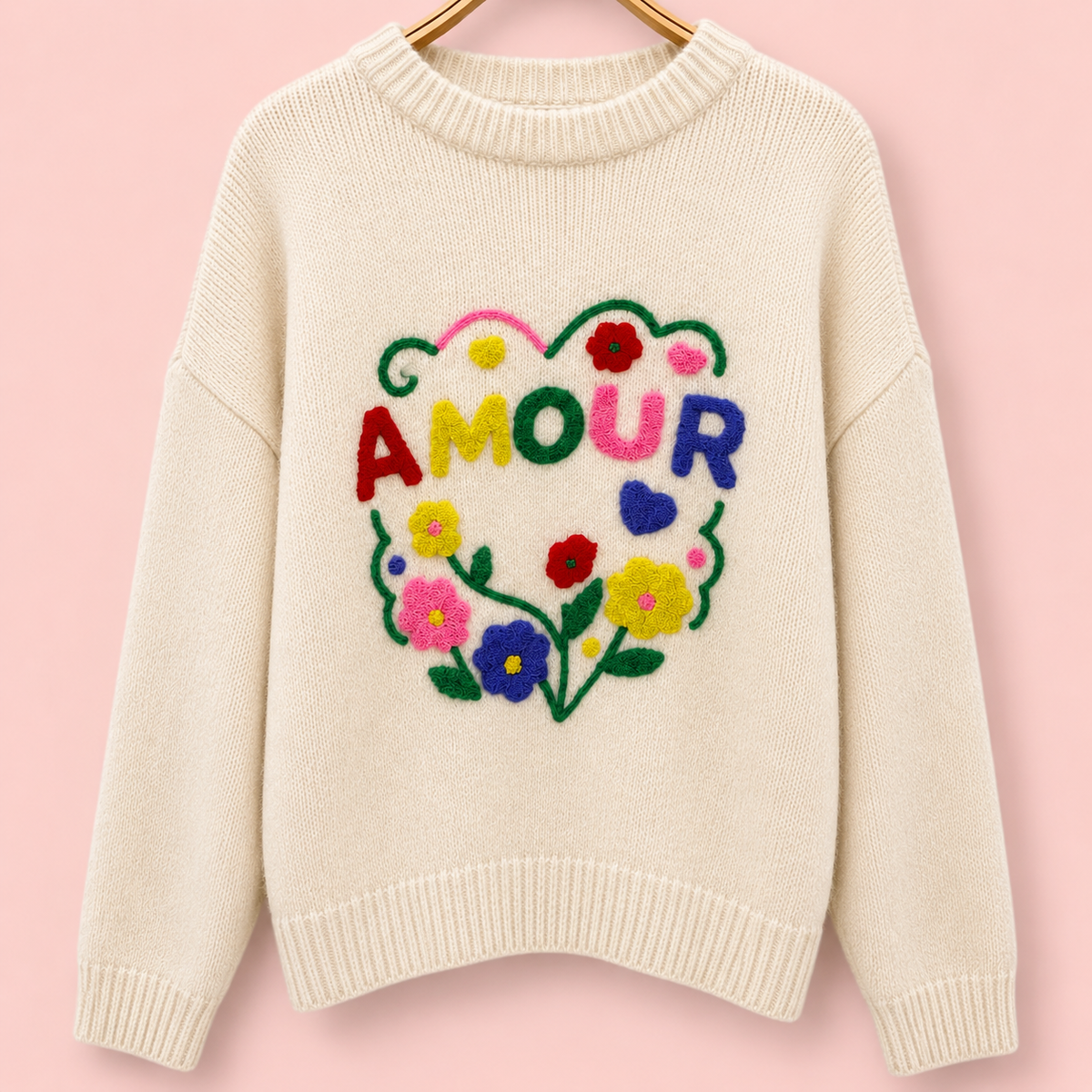 Back of cream knitted jumper with large colourful AMOUR embroidery surrounded by bright flowers and hearts.