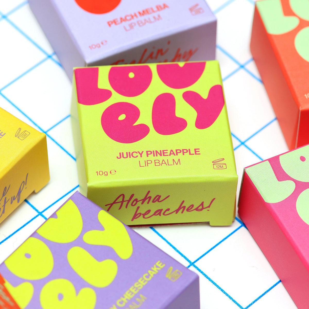 Grapefruit Lip Balm tin and colourful orange box displayed against a lilac tiled background.