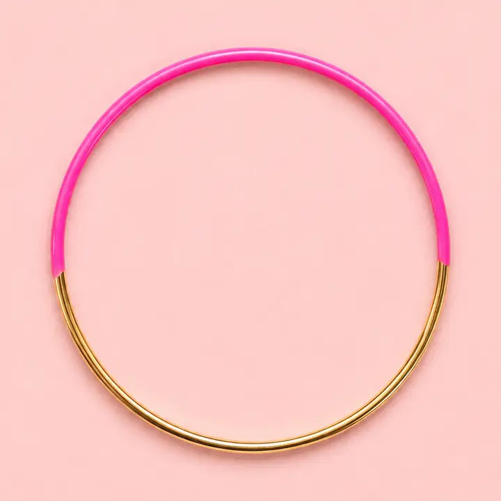 Vibrant pink dip enamel stacking bangle with polished gold tone detailing on a pale pink background.