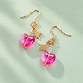 One of a kind gold plated drop earrings with hot pink glass heart beads, tiny pearl details and dangling gold star details on a pale mint background.