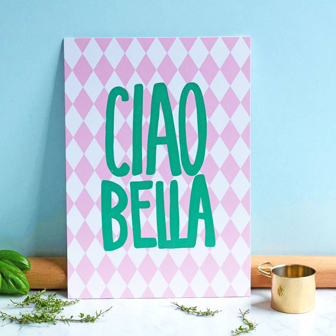Bright Ciao Bella A5 print with green lettering and a pink harlequin pattern, styled in a cheerful kitchen setting.