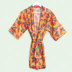 Vibrant peach kimono robe with multicoloured tropical leaves, wide sleeves and a matching waist tie displayed on a hanger.