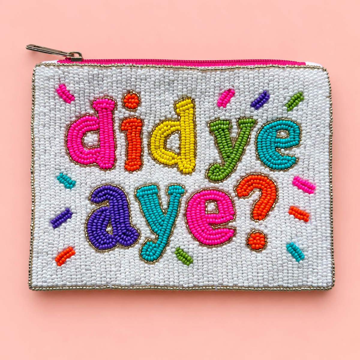 White beaded pouch with colourful Did Ye Aye lettering, multicoloured confetti details and bright pink zip on a pale pink background.