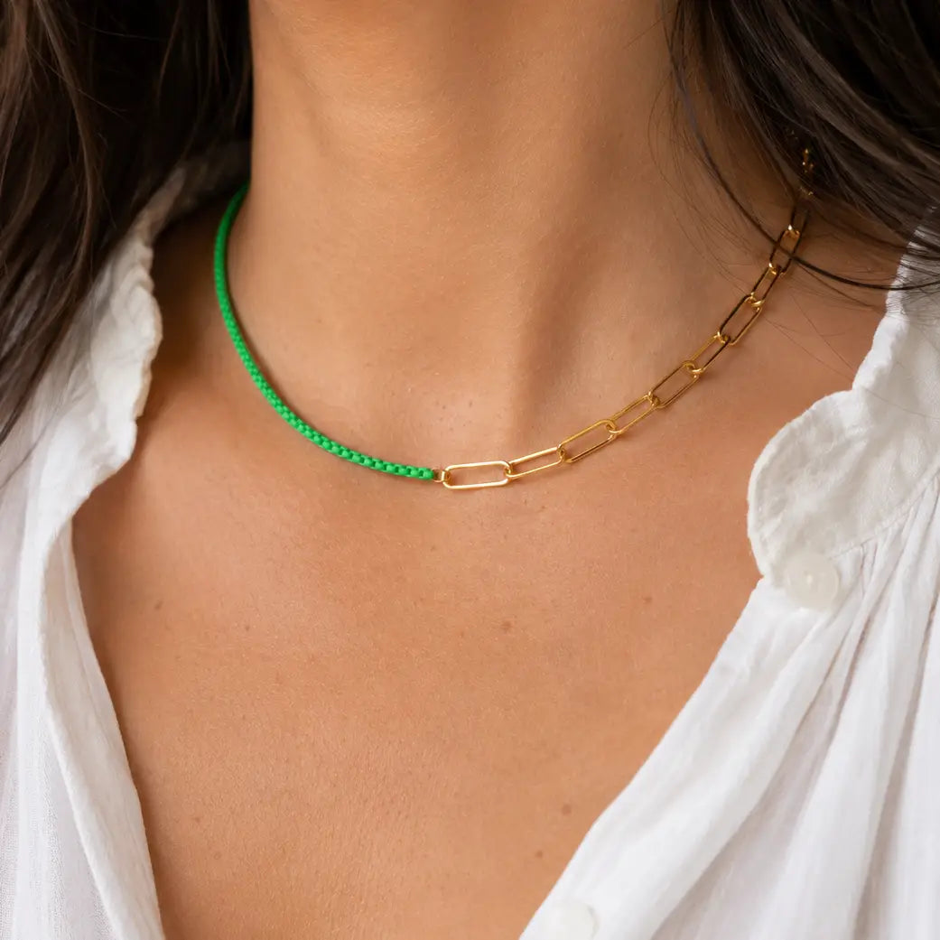 Two tone green and gold chain necklace worn with a white shirt.