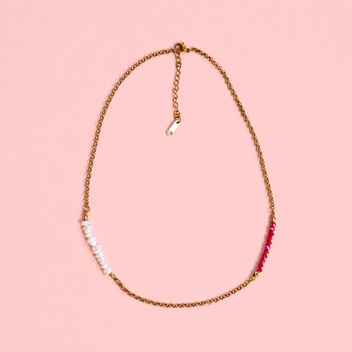 Gold tone chain necklace with white pearl beads and raspberry pink faceted beads on a soft pink background.