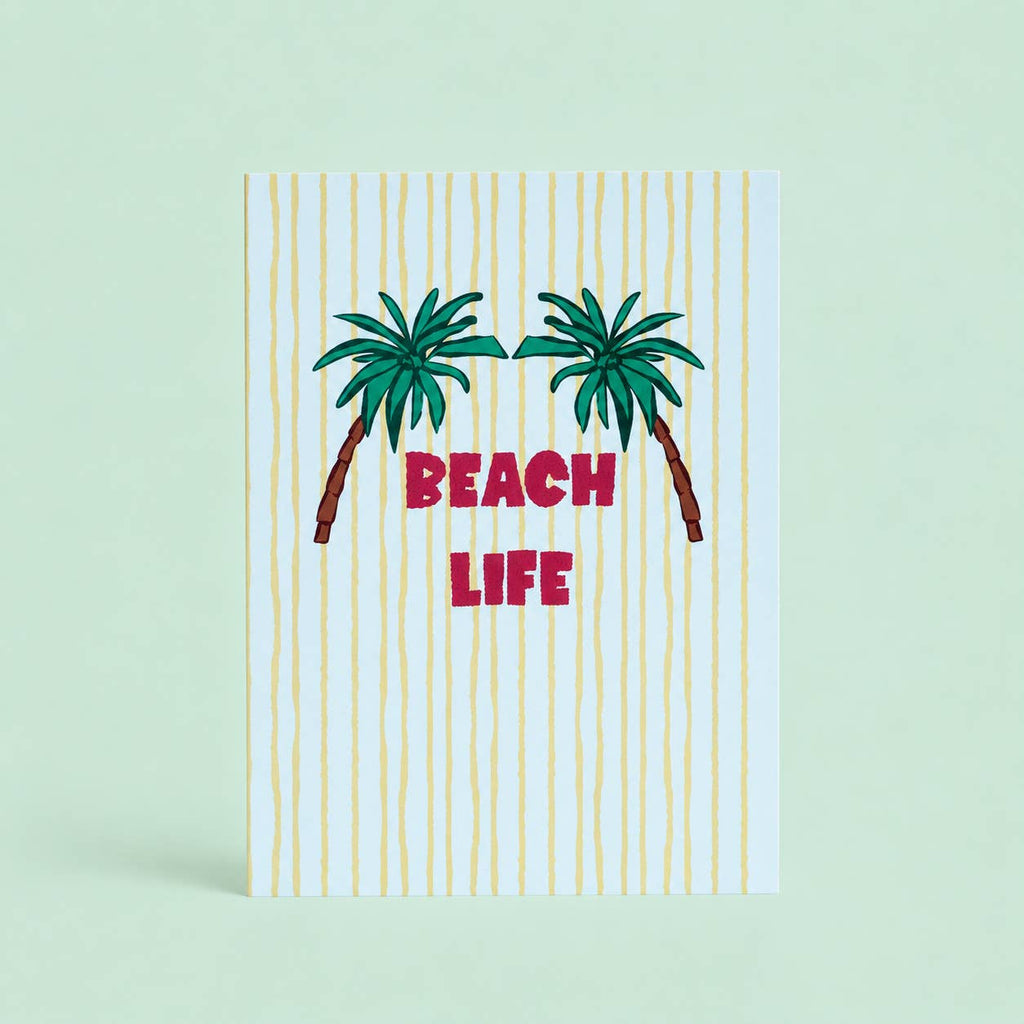 Cheerful Beach Life A5 print with two green palm trees, pink lettering and sunny yellow stripes on a pale background.