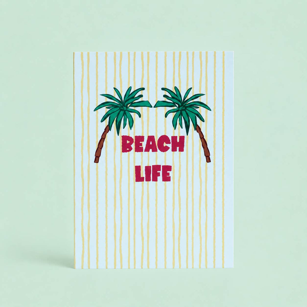 Cheerful Beach Life A5 print with two green palm trees, pink lettering and sunny yellow stripes on a pale background.
