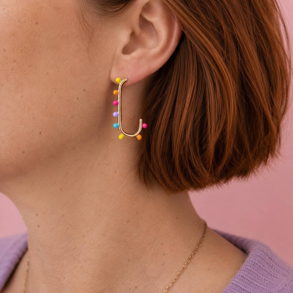 Colourful dotted gold tone statement earring worn on the ear.