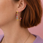 Colourful dotted gold tone statement earring worn on the ear.