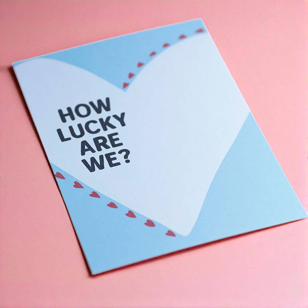Sweet How Lucky Are We? heart art print in pastel blue, white and red, displayed against a soft pink background.