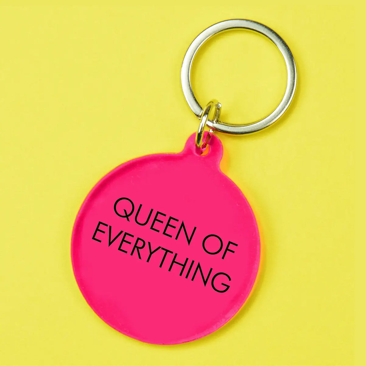 Hot pink round statement keyring with black Queen of Everything lettering and silver-tone metal keyring attachment.