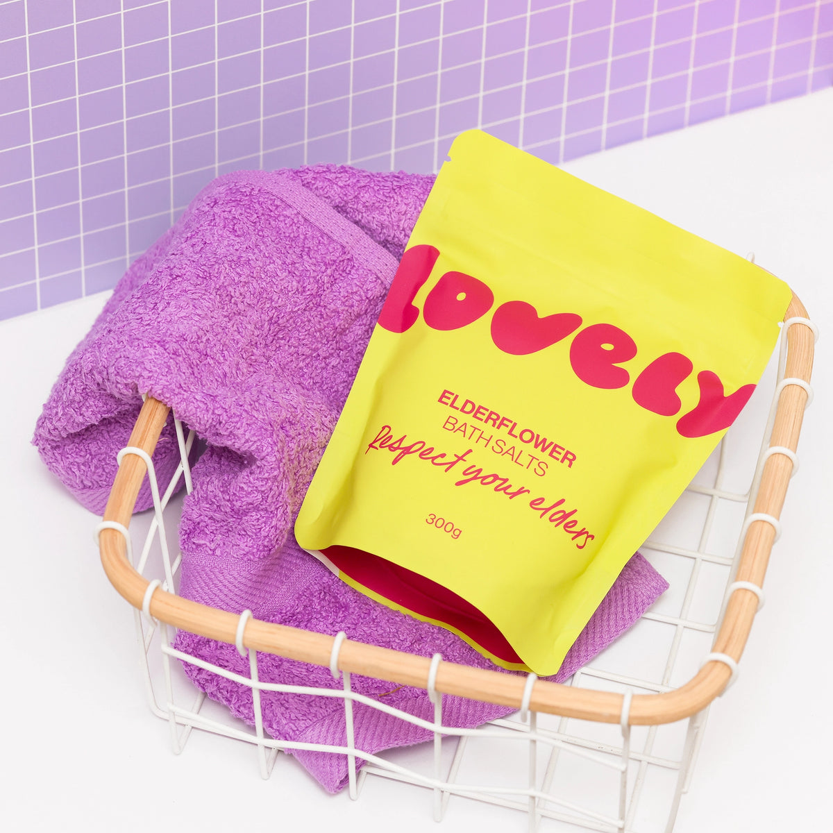 Elderflower Bath Salts displayed with a purple towel in a bathroom setting.