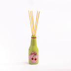 Green Cherry Soda reed diffuser bottle with natural reeds against a simple white background.