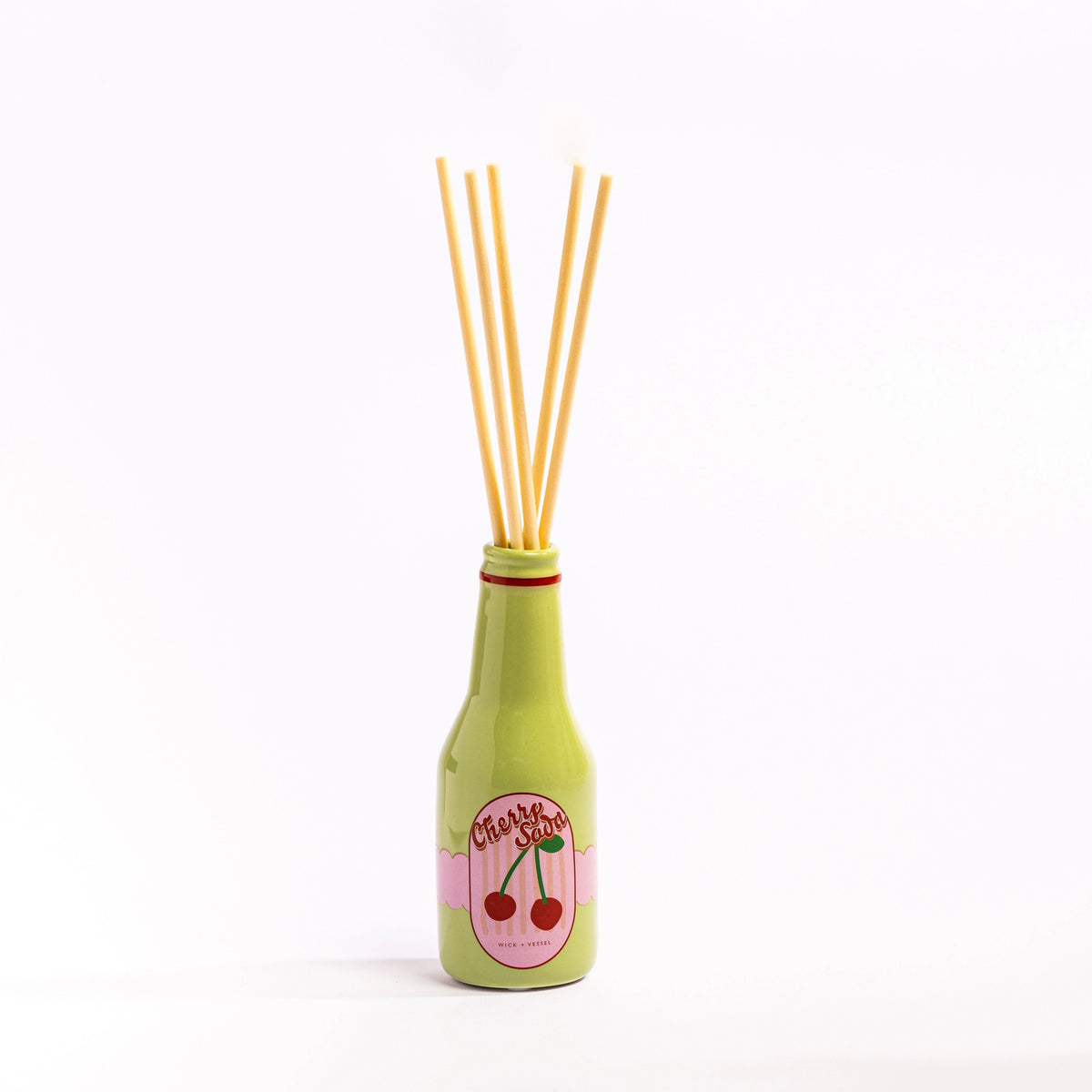 Green Cherry Soda reed diffuser bottle with natural reeds against a simple white background.