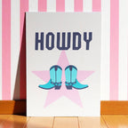 Colourful Howdy A5 art print featuring turquoise cowboy boots over a pink star with bold navy lettering.