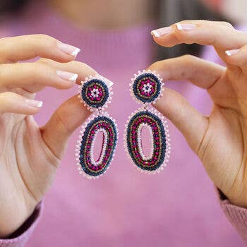 Pair of pink and blue beaded oval statement earrings held up to show their size and detailing.