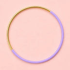 Lilac dip enamel stacking bangle with a polished gold tone finish on a pale pink background.