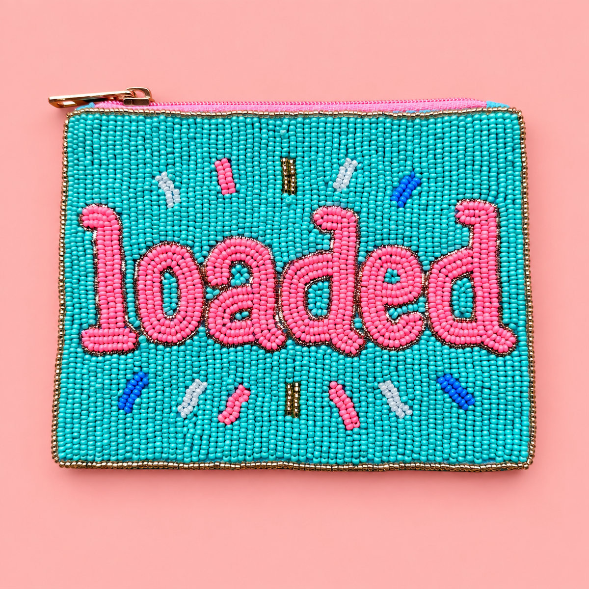 A square turquoise beaded pouch with pink embroidered lettering reading 'loaded' and small multicolor decorative accents, shown on a solid pink background.