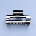 Black and white striped acrylic claw hair clip with a glossy finish on a soft pale blue background.