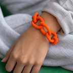Orange chunky beaded chain bracelet worn on the wrist showing its bold textured interlocking links.