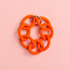 Chunky orange beaded statement chain bracelet with oversized interlocking links on a soft pink background.