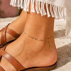 Multicoloured beaded gold infinity anklet worn around the ankle with brown sandals.