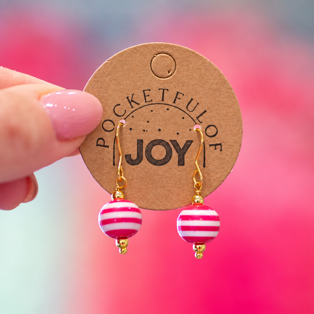 Pink and white striped acrylic drop earrings with gold tone details on a Pocketful of Joy card.