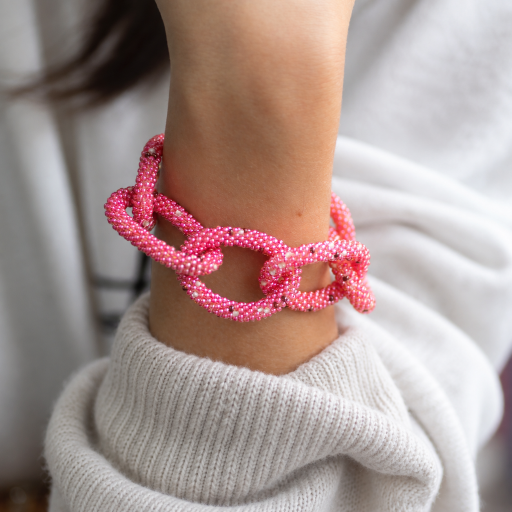 Chunky pink beaded statement chain bracelet worn on the wrist with oversized textured interlocking links.
