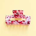 Pink confetti effect acrylic claw hair clip with red, white and berry coloured flecks on a soft butter yellow background.