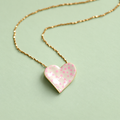 Limited edition gold plated heart necklace with cream enamel and pink polka dots on a soft pale green background.