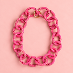 Chunky pink mix beaded statement chain necklace with oversized interlocking links and gold tone ring fastening on a soft pink background.