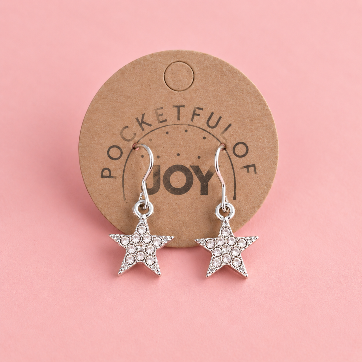Silver tone crystal star drop earrings displayed on a Pocketful of Joy card against a soft pink background.
