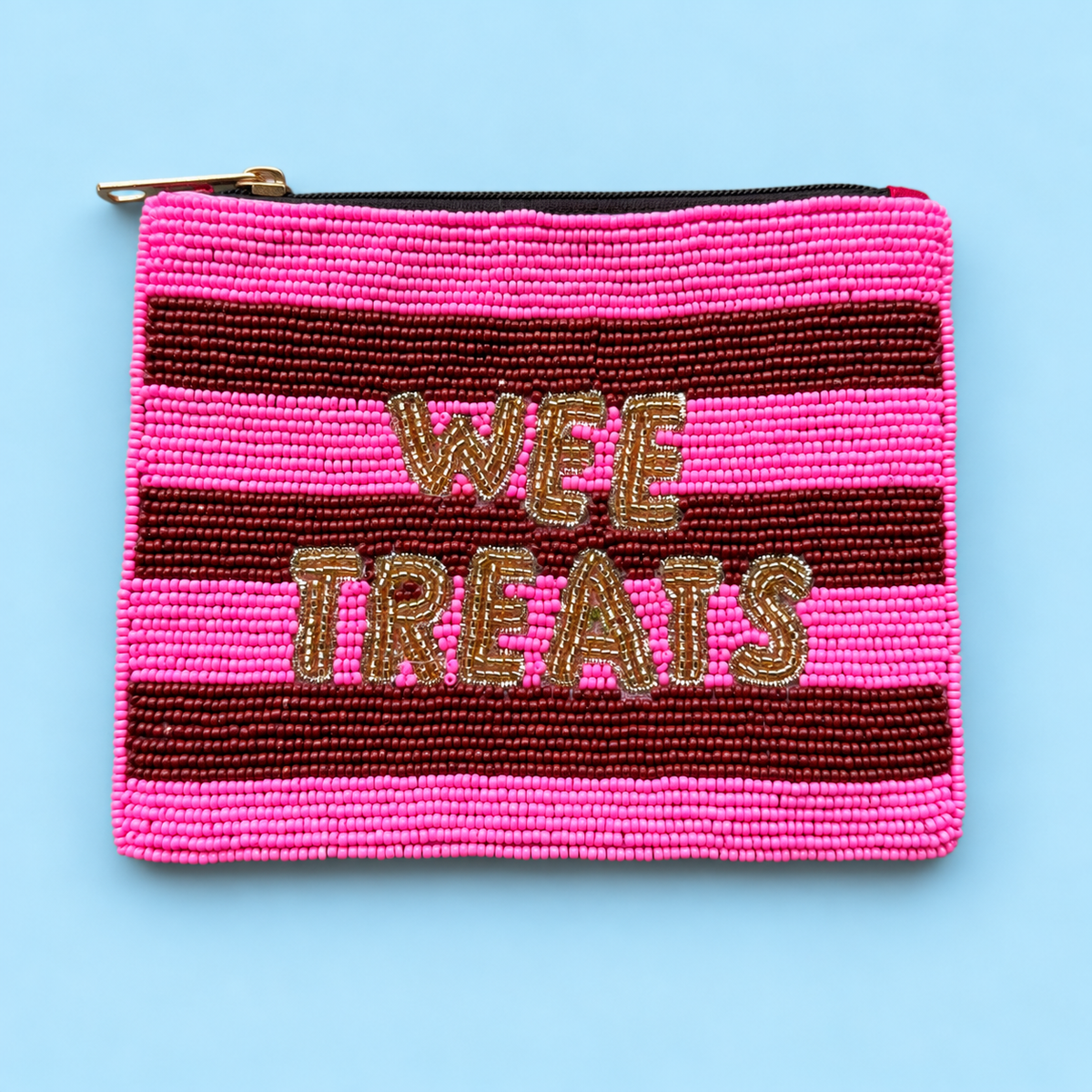 A rectangular beaded zipper pouch with horizontal pink and dark red stripes and the words 'WEE TREATS' in gold lettering, shown on a light blue background.