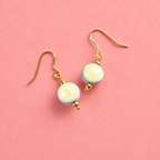 Retro yellow and multicoloured striped acrylic drop earrings with gold tone hooks on a soft coral pink background.